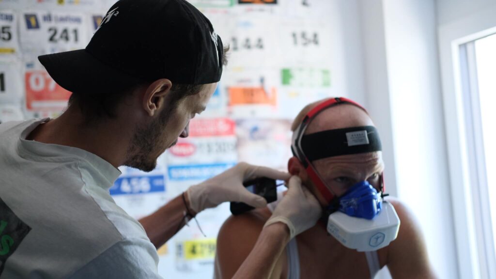 Laktattest Sport Sportwissenschaftler Massimo Köstl-Lenz nimmt einem Athleten beim Leistungstest am eigenen Fahrrad Blut am Ohr ab und führt eine präzise Leistungsdiagnostik mit Laktattest im Ausdauersport durch.