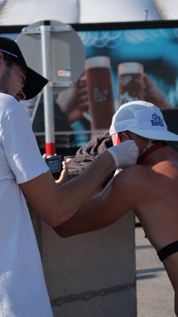 Laktattest Laufen Sportwissenschaftler Massimo Köstl-Lenz nimmt einem Läufer nach einem Testlauf Blut am Ohr ab und setzt mobile Leistungsdiagnostik mit Laktattest im Ausdauersport ein.