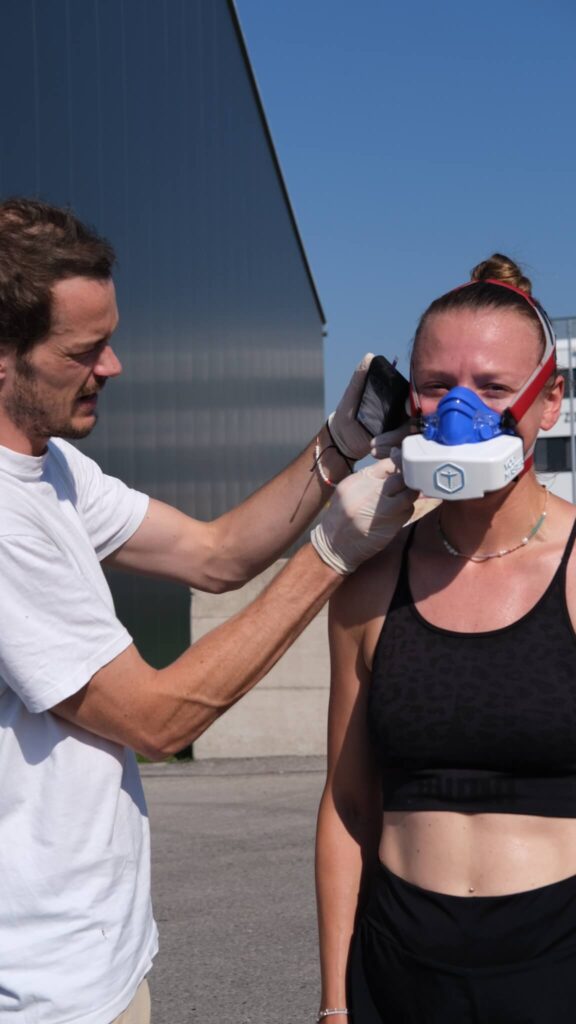 Sportwissenschaftler Massimo Köstl-Lenz führt bei einer Athletin mit VO2MASTER-Maske im Freien eine Leistungsdiagnostik mit VO2max-Leistungstest im Laufen durch.