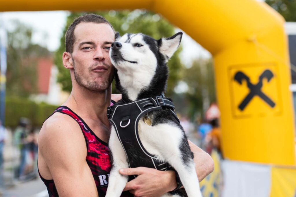 Massimo Köstl-Lenz im Ziel des Strasshofer Herbstlaufs, wo er seine Hündin in die Arme nimmt und beide sichtlich verbunden in die Kamera blicken.