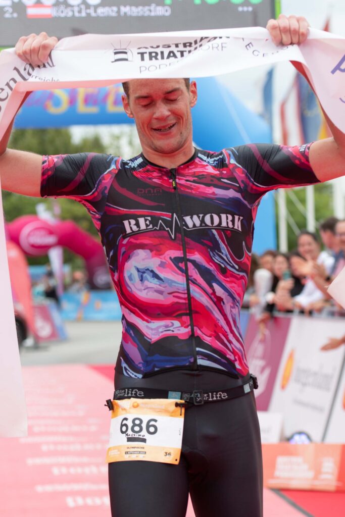 Massimo Köstl-Lenz jubelt als Leistungssportler beim Austria Triathlon Podersdorf über den zweiten Platz auf der olympischen Distanz und zeigt, wofür er als Triathlon Trainer steht.