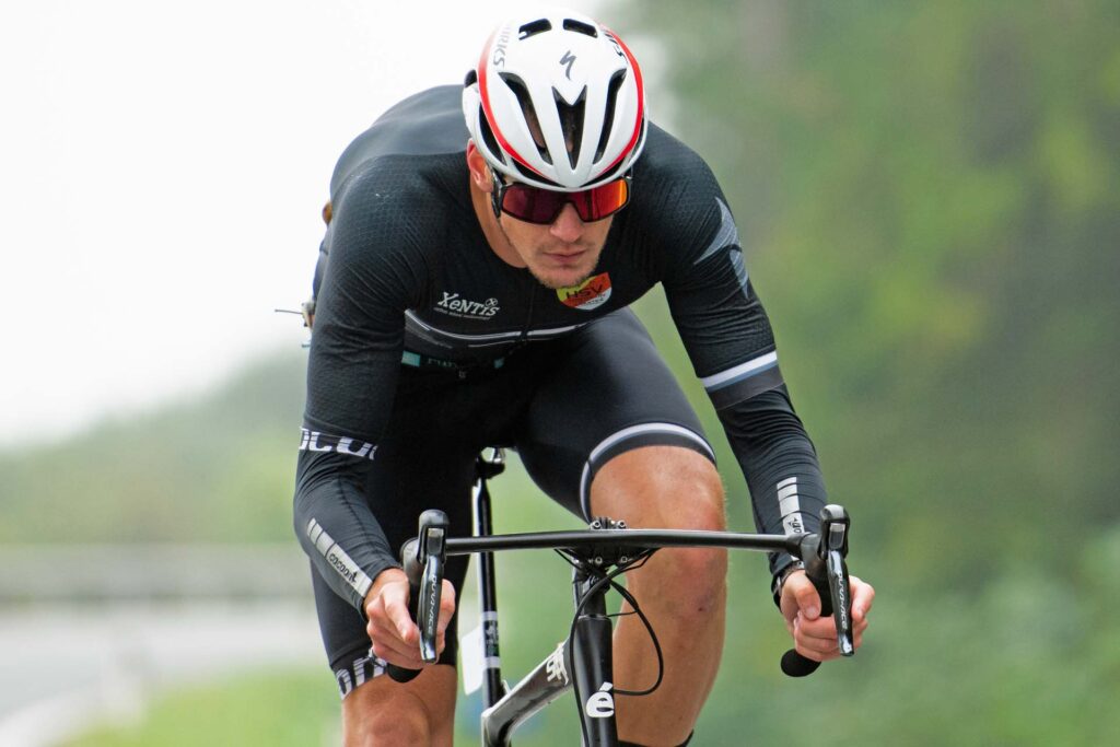 Triathlon Trainer Massimo Köstl-Lenz in aerodynamischer Position am Rennrad an einem kühlen, nebligen Morgen während eines Triathlons.