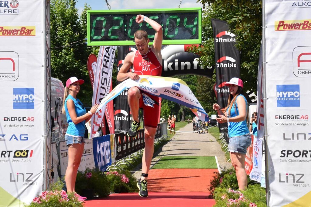 Massimo Köstl-Lenz feiert beim Triathlon in Linz über die olympische Distanz den Tagessieg und springt jubelnd ins Ziel.