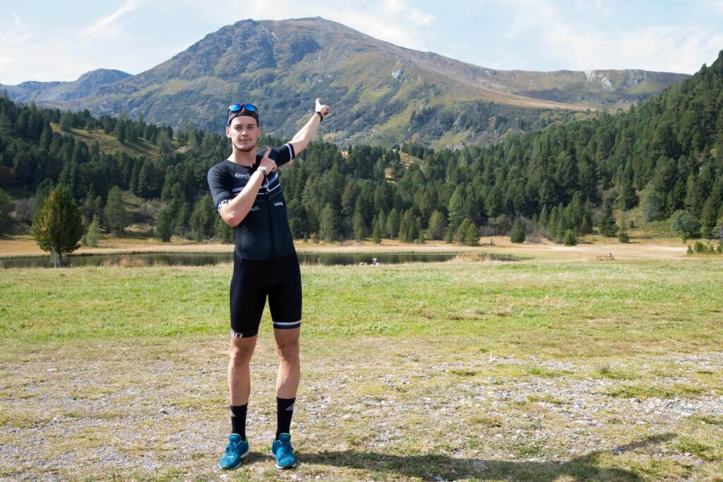 Massimo Köstl-Lenz zeigt als Triathlon Trainer von MKL Training auf einen Berg und symbolisiert den Weg zum sportlichen Ziel.