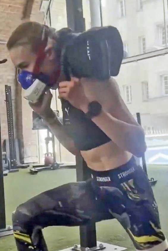 Hyrox-Sportlerin im Ausfallschritt mit VO2-Master-Maske und Gewicht auf den Schultern während der mobilen Leistungsdiagnostik in der Race-Simulation.