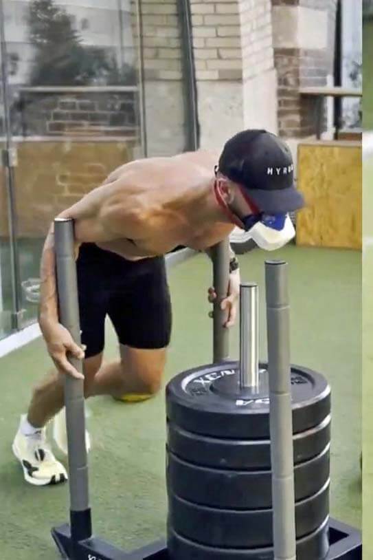 Der Hyrox-Weltmeister absolviert im Gym einen Sled Push mit VO2-Master-Maske während der mobilen Leistungsdiagnostik in der Wettkampf-Simulation.