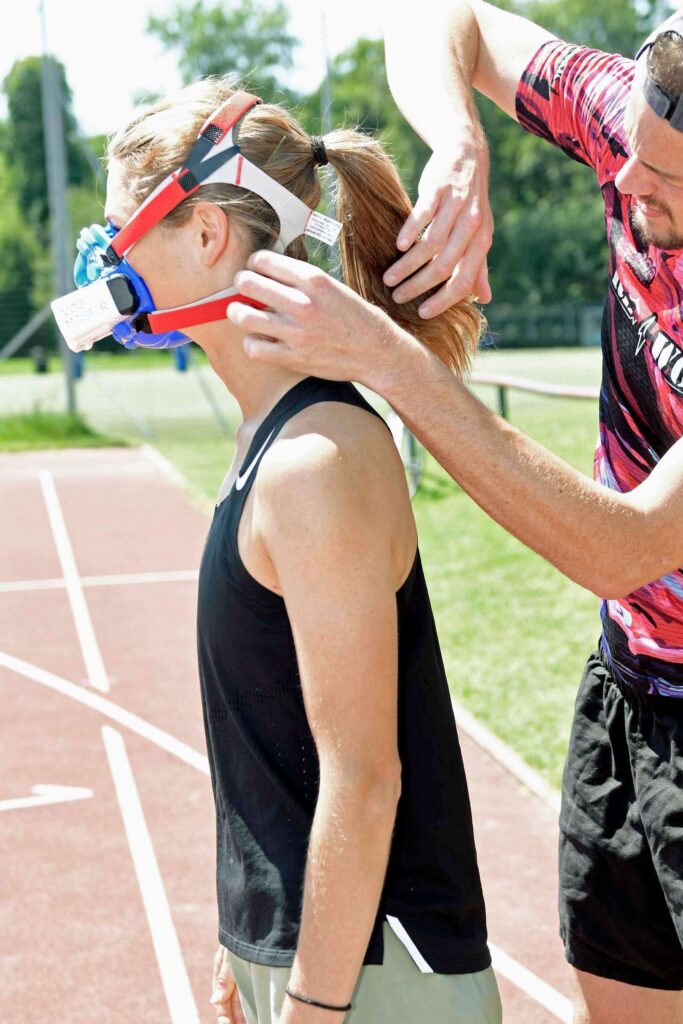 Sportwissenschaftler Massimo Köstl-Lenz passt Lemi, österreichische Spitzenläuferin und mehrfache Titelträgerin, vor der mobilen Leistungsdiagnostik die VO₂-Master-Maske an.